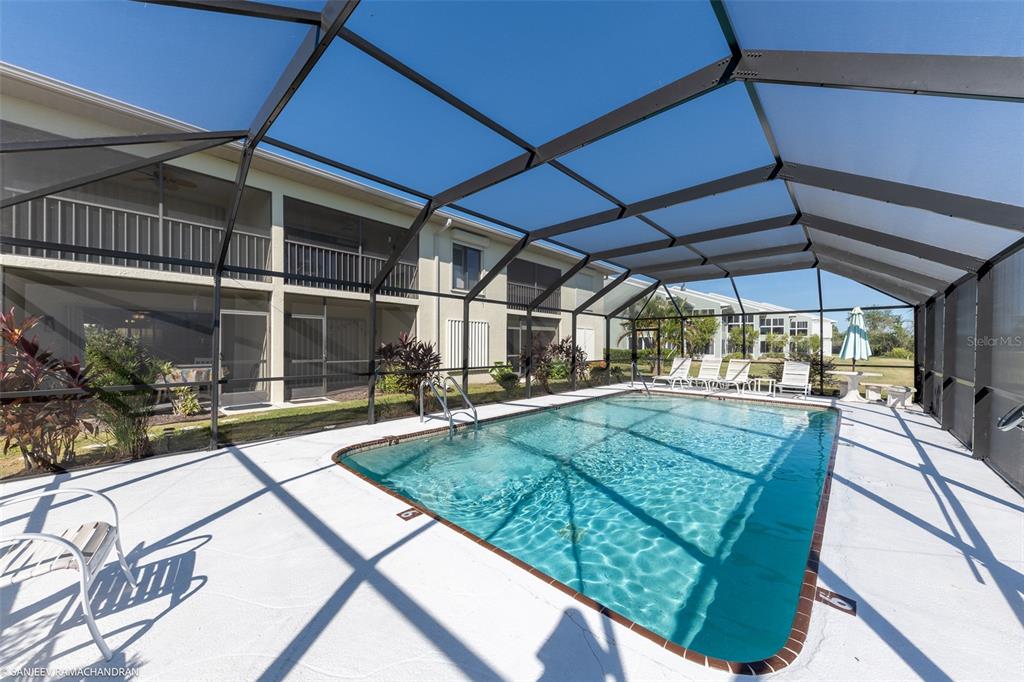A screened-in swimming pool sits on a concrete patio next to a multi-story building — 1416 SAN CRISTOBAL AVENUE UNIT 3 (C), PUNTA GORDA, FL