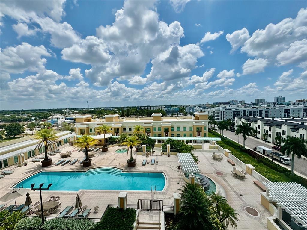 An elevated view of a swimming pool area with palm trees and surrounding apartment buildings — 800 N TAMIAMI TRAIL UNIT 708, SARASOTA, FL