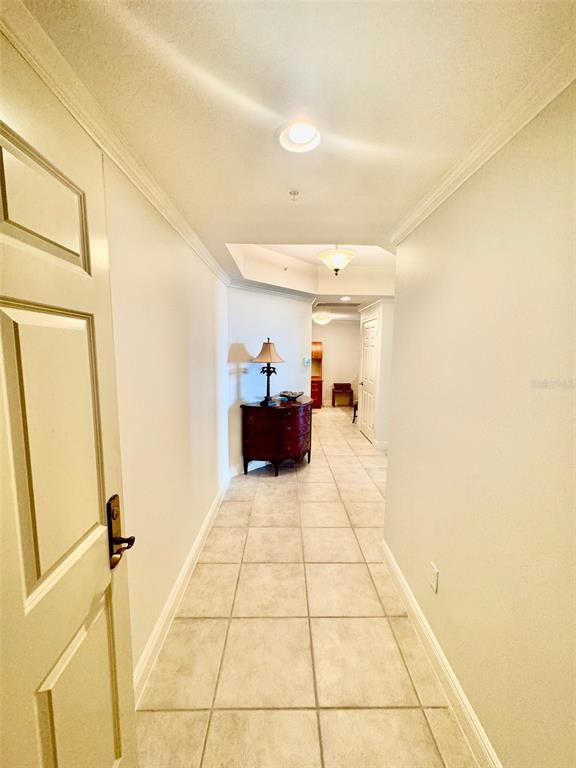 A hallway with light-colored tile flooring leads to a dark wood chest and lamp — 800 N TAMIAMI TRAIL UNIT 708, SARASOTA, FL