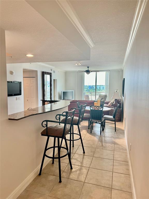 A kitchen breakfast bar with stools overlooks a living and dining area with balcony access — 800 N TAMIAMI TRAIL UNIT 708, SARASOTA, FL