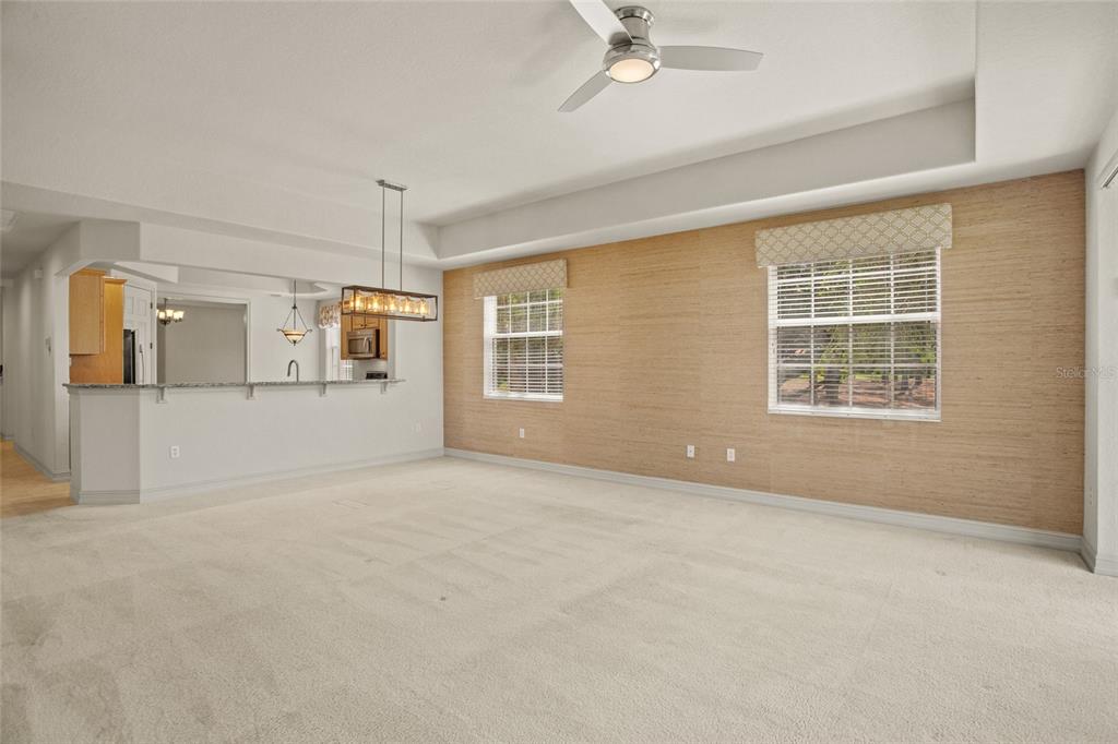 A spacious living room features beige carpeting, a textured accent wall, and a ceiling fan — 26207 AVENIDA LAS COLINAS, HOWEY IN THE HILLS, FL