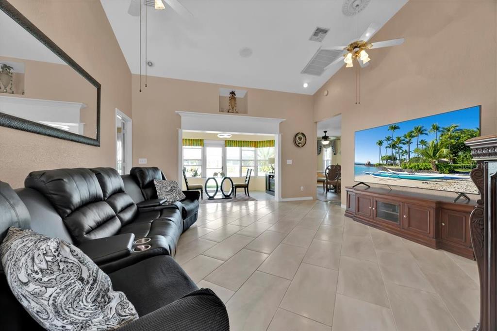 A living room features a black leather sofa, tile flooring, and a large wall-mounted television — 543 CLUBHILL DRIVE, HAINES CITY, FL
