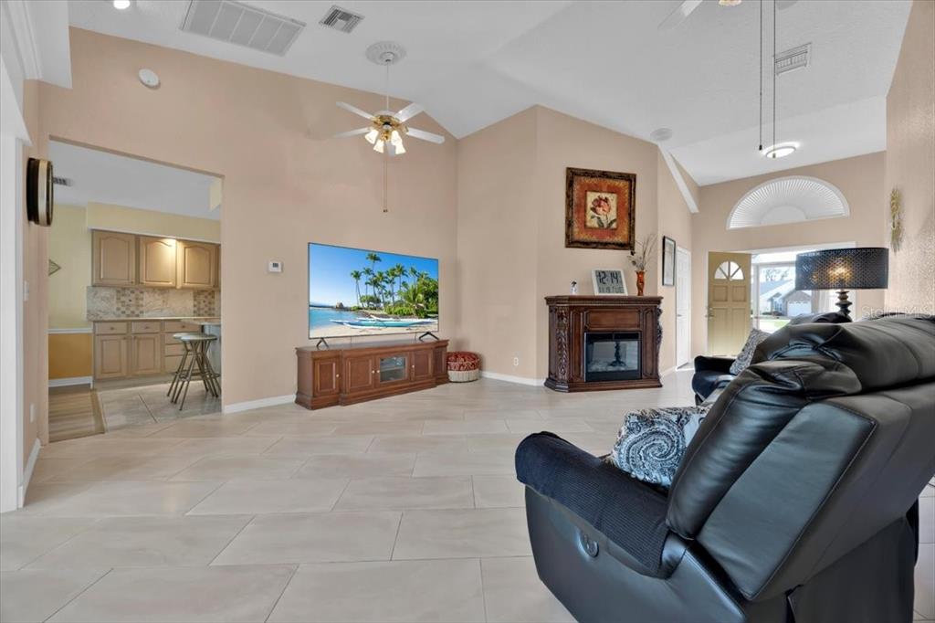 A living room with tile floors, a fireplace, a television, and an open kitchen — 543 CLUBHILL DRIVE, HAINES CITY, FL