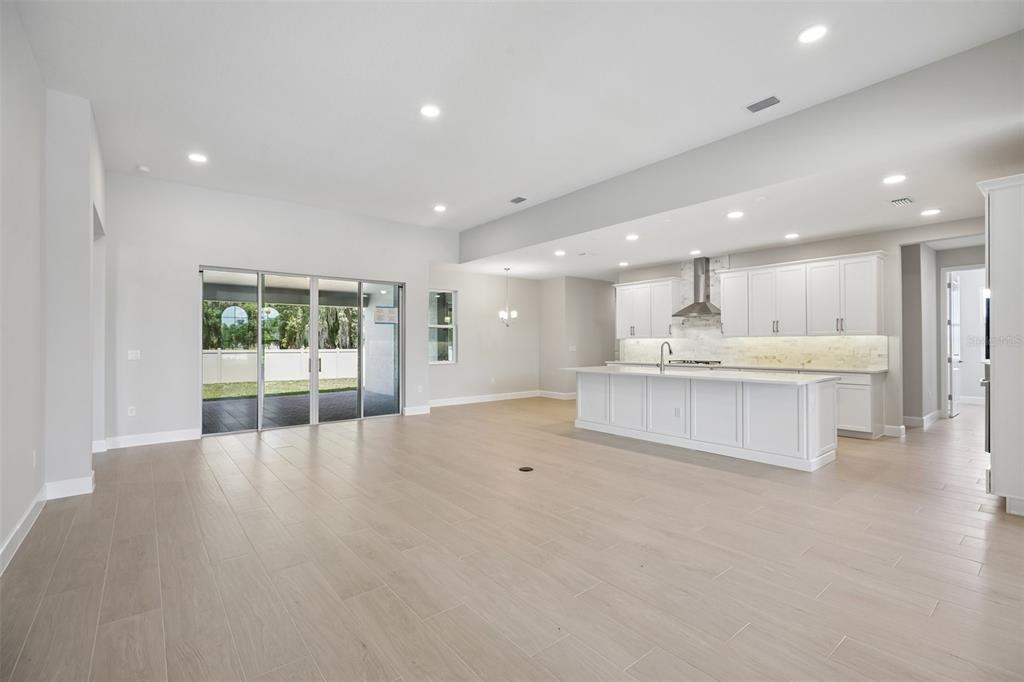An open-concept living room and kitchen featuring a gray sofa, wood furniture, and sliding doors — 3802 WOLVES CREEK PLACE, APOPKA, FL
