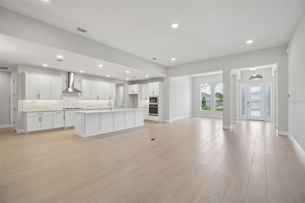 A home office features a wooden desk, two patterned chairs, a blue rug, and a window — 3802 WOLVES CREEK PLACE, APOPKA, FL