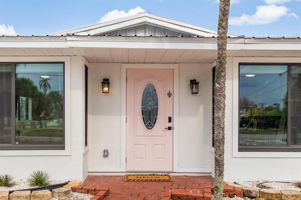 A light pink front door with a glass insert sits between two large windows — 1950 NEBRASKA AVENUE, ENGLEWOOD, FL