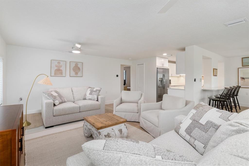 A living room features light-colored furniture, a wooden coffee table, and an open kitchen area — 1950 NEBRASKA AVENUE, ENGLEWOOD, FL