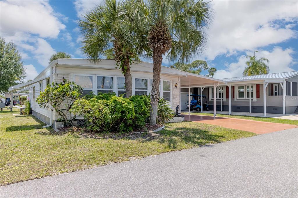 A single-story manufactured home with a carport, palm trees, and a golf cart parked outside — 2100 KINGS HIGHWAY UNIT 336, PUNTA GORDA, FL