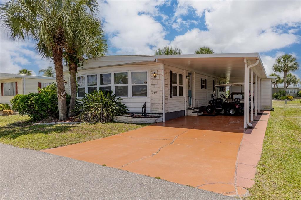 A single-story mobile home features a carport, a paved driveway, and a palm tree — 2100 KINGS HIGHWAY UNIT 336, PUNTA GORDA, FL