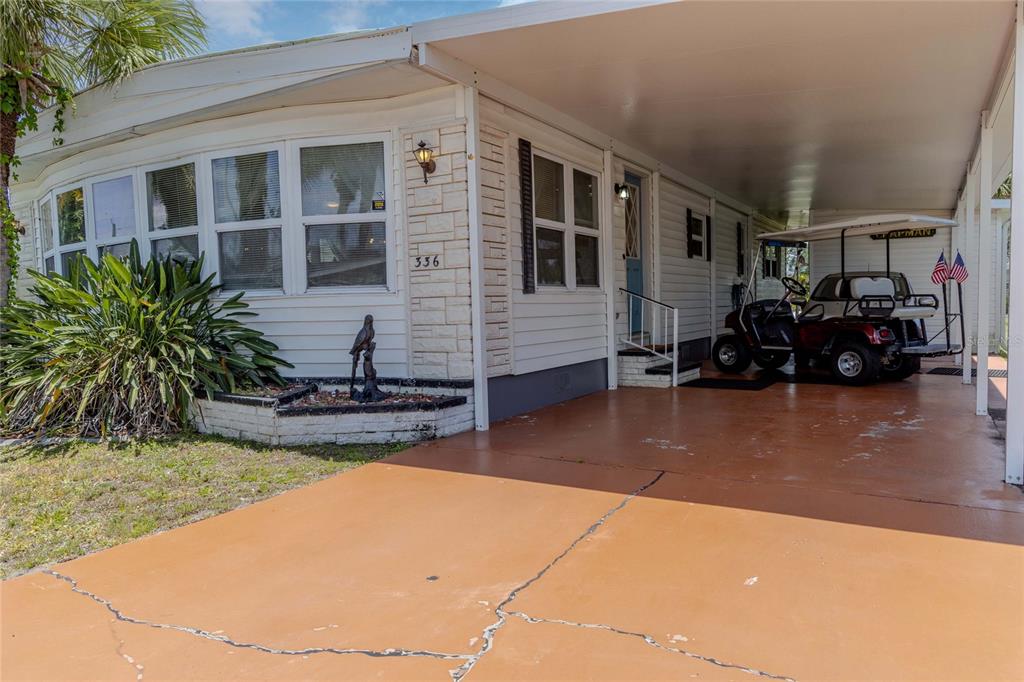 A mobile home exterior features a painted concrete driveway, a carport, and a golf cart — 2100 KINGS HIGHWAY UNIT 336, PUNTA GORDA, FL