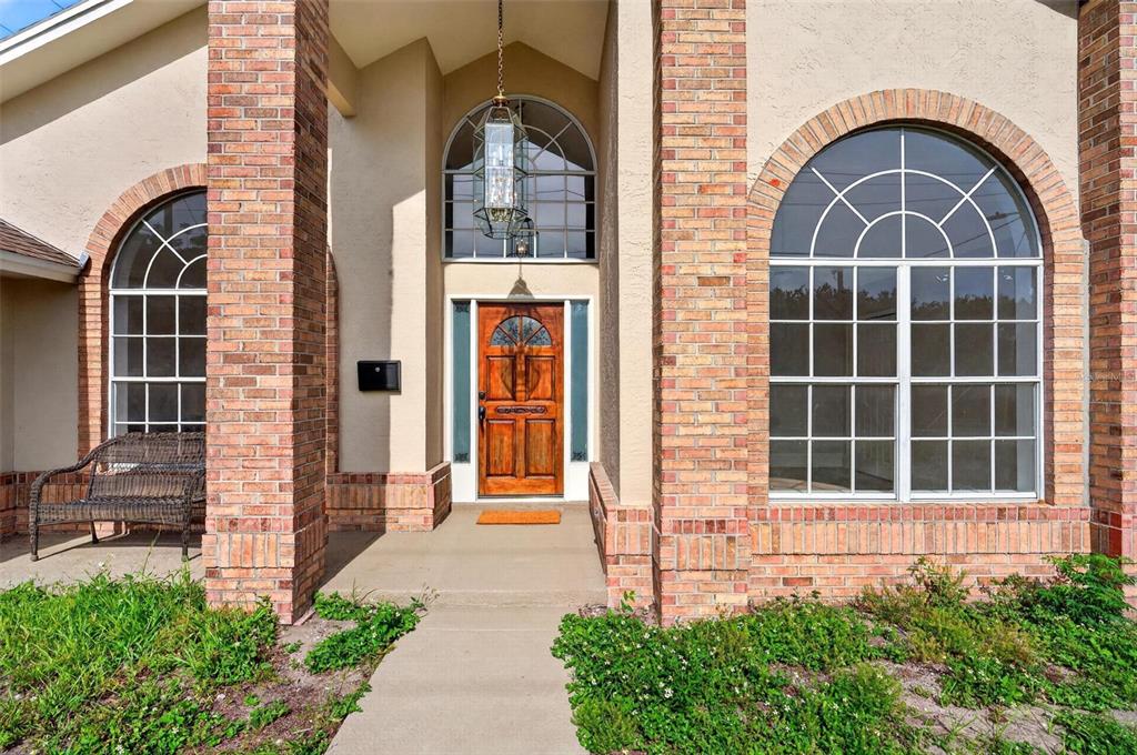 A front entryway features a wooden door, arched windows, and brick columns under a covered porch — 2800 CONWAY GARDENS ROAD, ORLANDO, FL