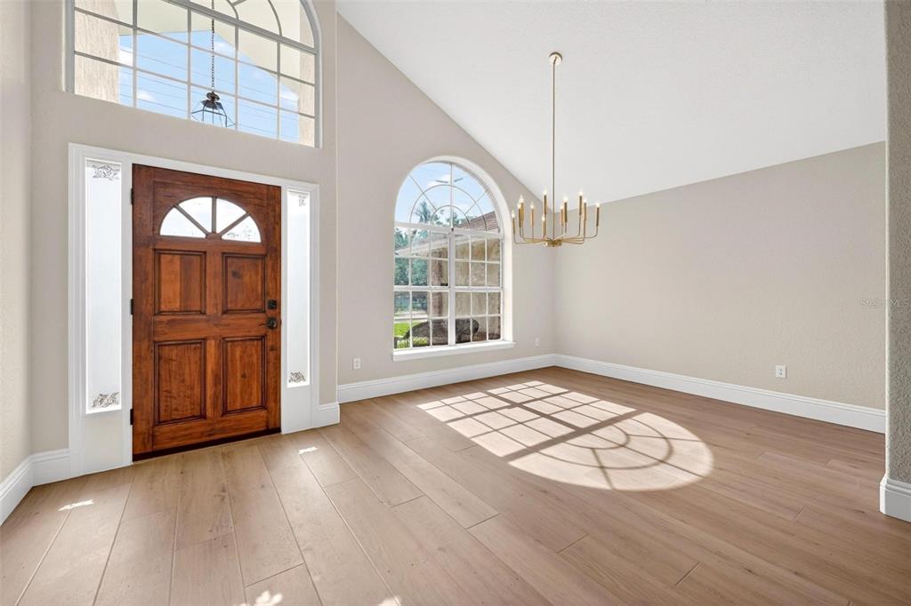 An entryway with light wood floors, a vaulted ceiling, a chandelier, and a wooden front door — 2800 CONWAY GARDENS ROAD, ORLANDO, FL