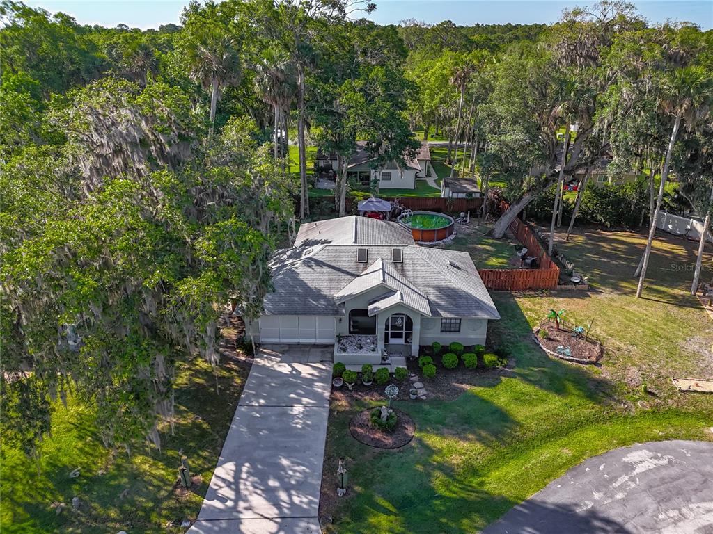 An aerial view shows a single-story house with a driveway, yard, and above-ground pool — 27 BLACK HAWK PLACE, PALM COAST, FL
