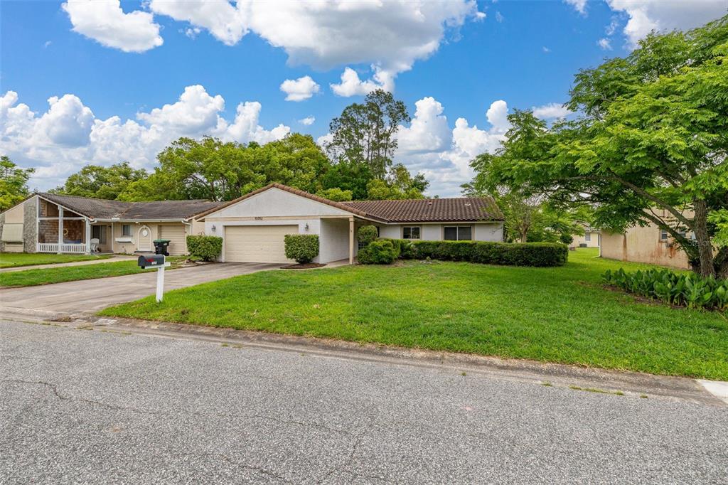 A single-story house with a two-car garage, a tiled roof, and a front lawn — 10702 WILLIAM TELL DRIVE, ORLANDO, FL