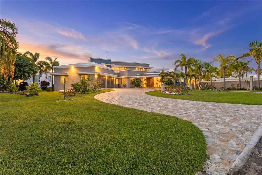 A modern two-story house with a stone driveway and palm trees at sunset — 10 URB MIRADOR DEL CIELO, ISABELA, PR