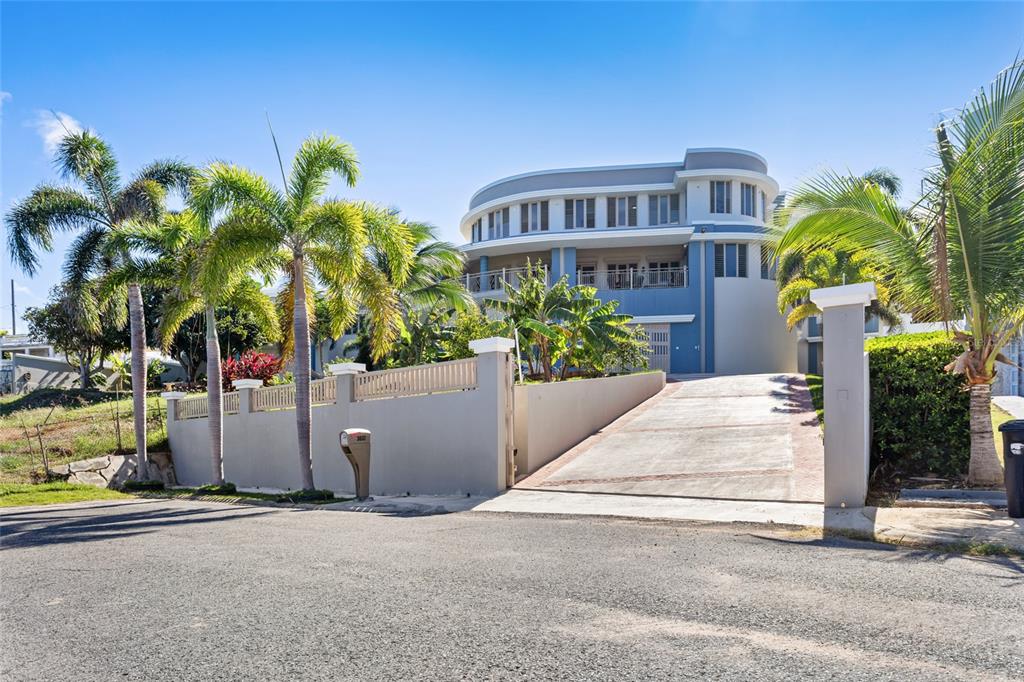 A multi-story house with a curved facade and a concrete driveway behind a perimeter wall — 10 URB MIRADOR DEL CIELO, ISABELA, PR