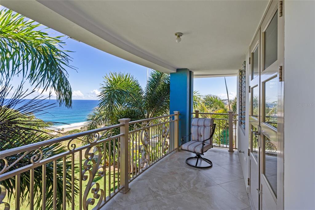 A covered balcony with tile flooring, a metal railing, and a view of the ocean — 10 URB MIRADOR DEL CIELO, ISABELA, PR