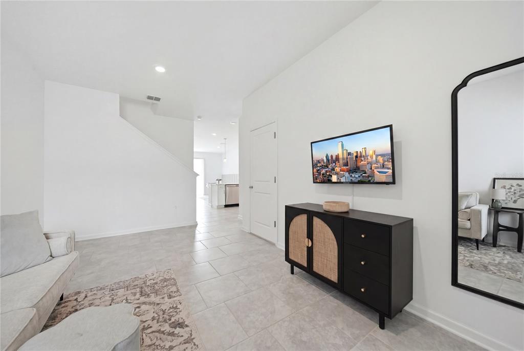 A living room features light tile flooring, a wall-mounted television, and a black storage cabinet — 3161 LAURENT LOOP, DAVENPORT, FL