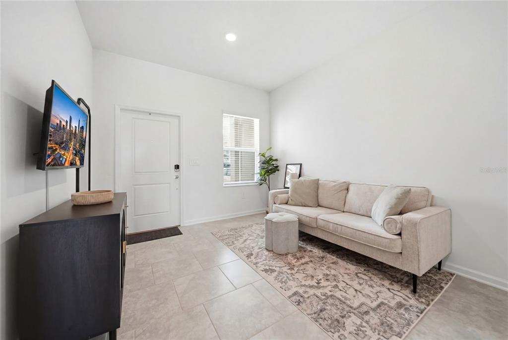 A living room features a beige sofa, a patterned rug, and a wall-mounted television — 3161 LAURENT LOOP, DAVENPORT, FL