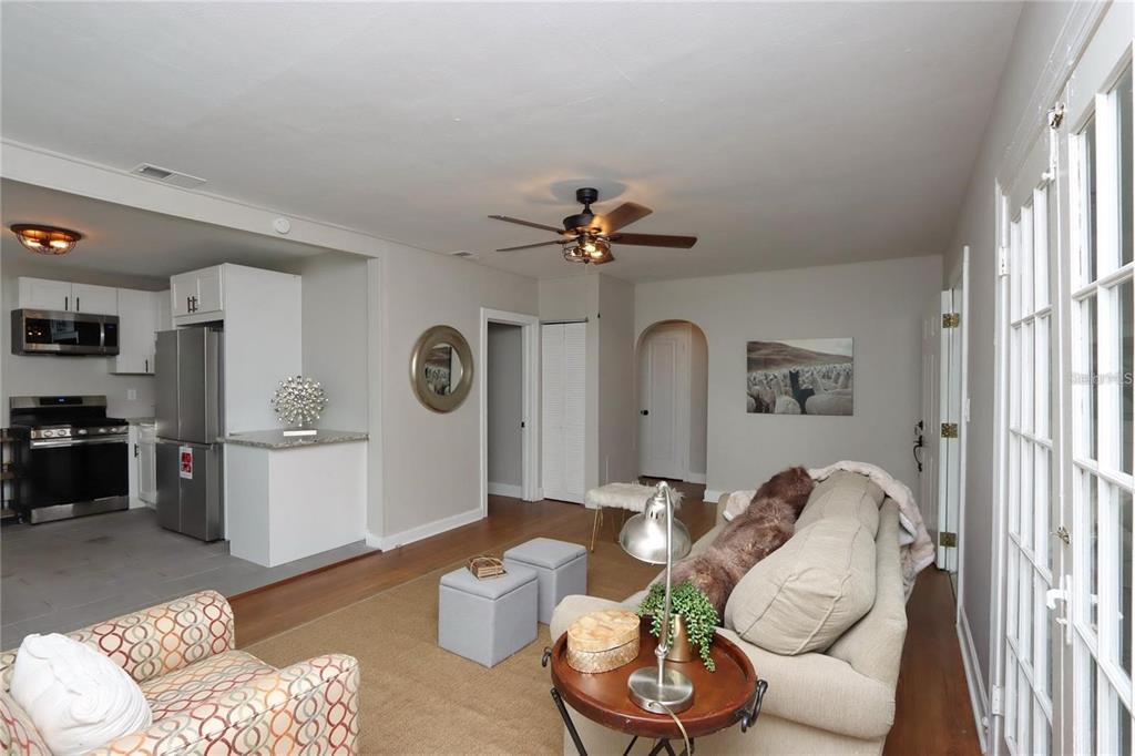 A living room with a beige sofa, patterned armchair, and an open kitchen area — 1532 13TH STREET S, ST PETERSBURG, FL