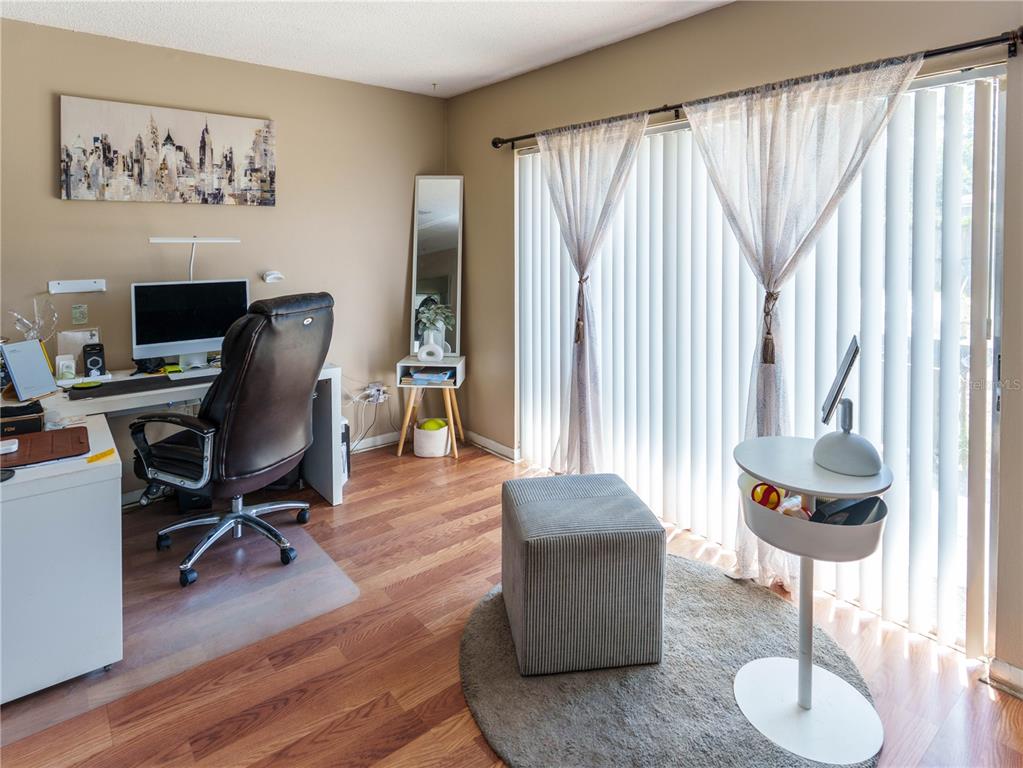 A home office features a desk, leather chair, gray ottoman, and sliding glass balcony doors — 5392 MARINER BOULEVARD, SPRING HILL, FL