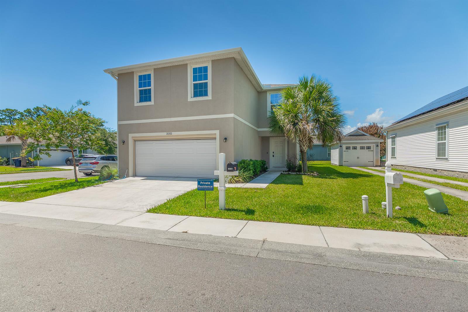 A two-story beige house with a two-car garage and a front lawn — 3351 Liberty Square Way, Fort Pierce FL 34982, FORT PIERCE, FL