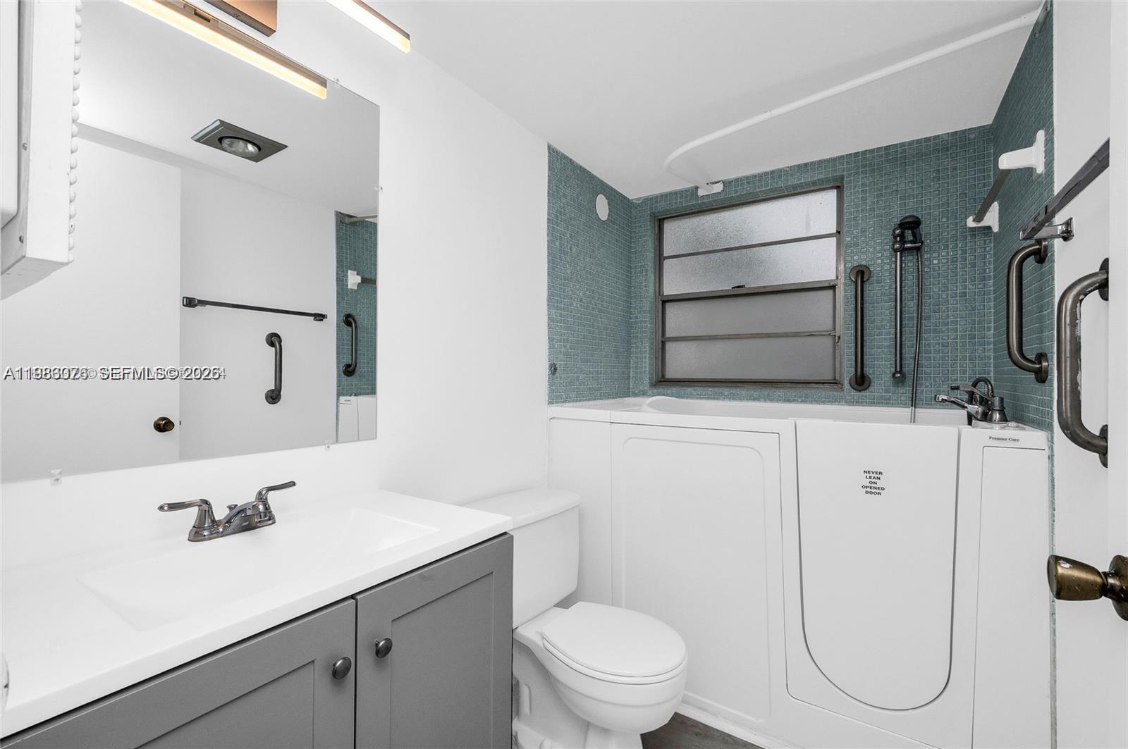 A bathroom features a white vanity with a sink, a toilet, and a wall mirror — 257 Fanshaw G # 257, Boca Raton FL 33434, BOCA RATON, FL