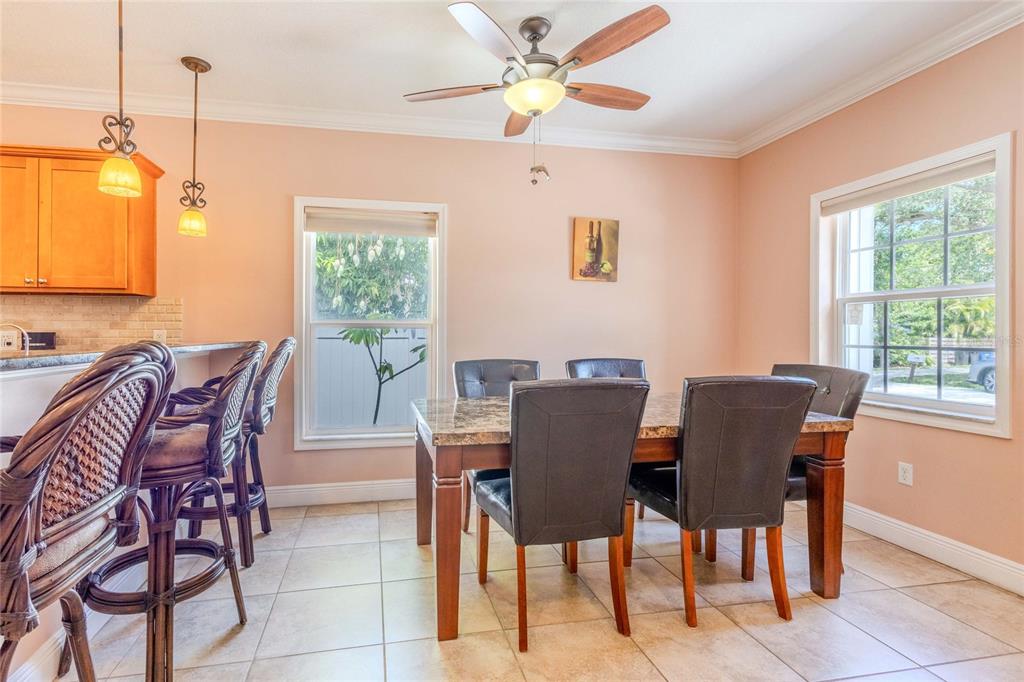 A dining area with a stone-topped table, dark chairs, tile flooring, and a ceiling fan — 2920 EDGEWOOD LANE, SARASOTA, FL