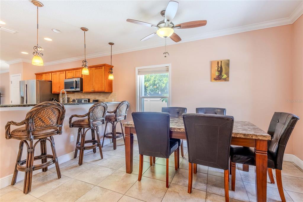 A dining area with a stone-topped table, dark chairs, and a breakfast bar with stools — 2920 EDGEWOOD LANE, SARASOTA, FL