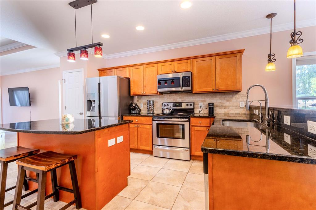 A kitchen features wood cabinets, stainless steel appliances, and a dark granite-topped island — 2920 EDGEWOOD LANE, SARASOTA, FL
