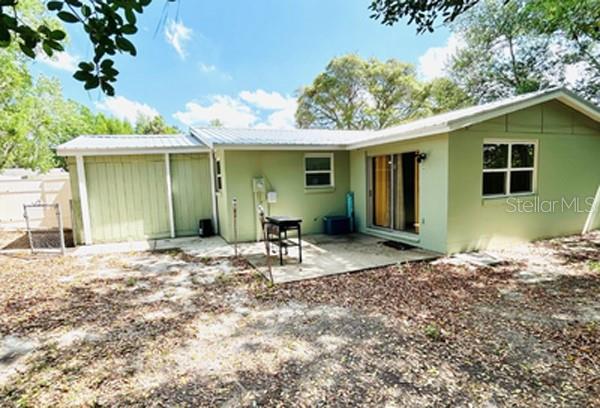 The exterior of a light green house features a concrete patio and a metal roof — 14536 SW 34TH TERRACE ROAD, OCALA, FL