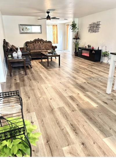 A living room features wood-look flooring, a brown sofa, a coffee table, and a ceiling fan — 14536 SW 34TH TERRACE ROAD, OCALA, FL