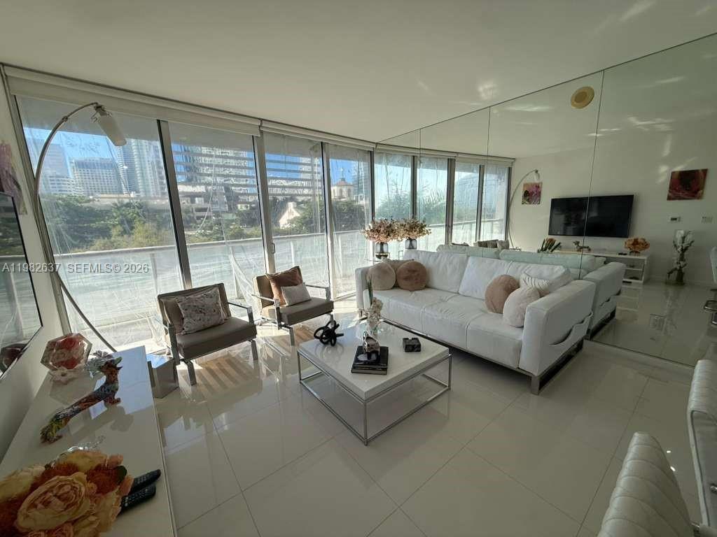 A bright living room features white tile floors, a white sofa, and floor-to-ceiling windows — 495 Brickell Ave # 511, Miami FL 33131, MIAMI, FL