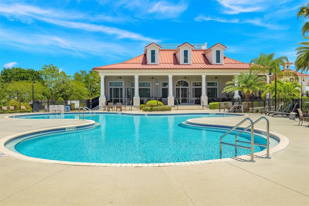 A swimming pool sits in front of a clubhouse with a red metal roof — 171 BLAZING STAR AVENUE, LAKE ALFRED, FL