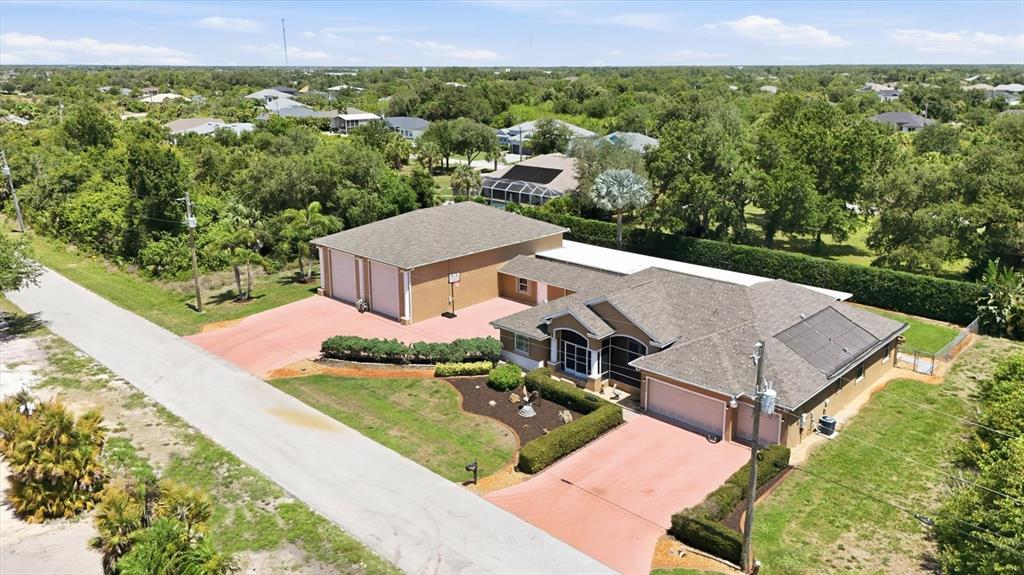 An aerial view shows a house with a detached garage, red driveways, and solar panels — 13346 CEDAR CITY AVENUE, PORT CHARLOTTE, FL