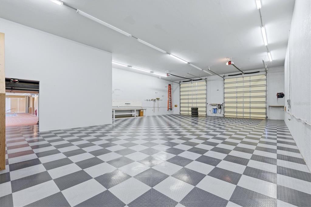 A spacious garage with a checkered floor, white walls, and two large roll-up doors — 13346 CEDAR CITY AVENUE, PORT CHARLOTTE, FL