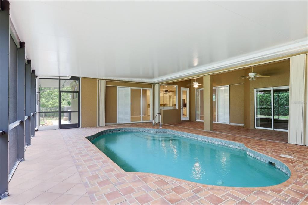 A covered lanai features a swimming pool with brick pavers and multiple sliding glass doors — 13346 CEDAR CITY AVENUE, PORT CHARLOTTE, FL