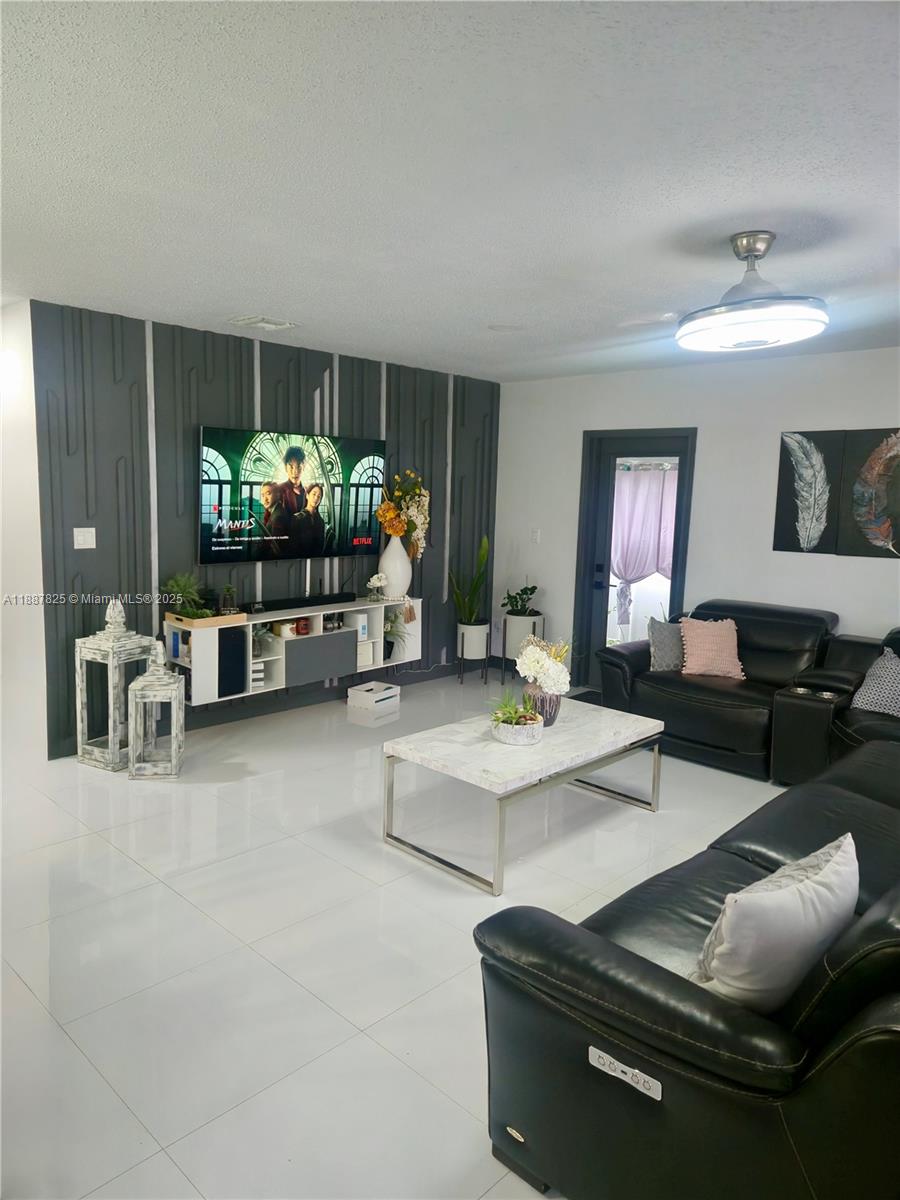 A living room features a dark accent wall with vertical molding, white tile floors, and furniture — 2150 NW 43rd St, Miami FL 33142, MIAMI, FL