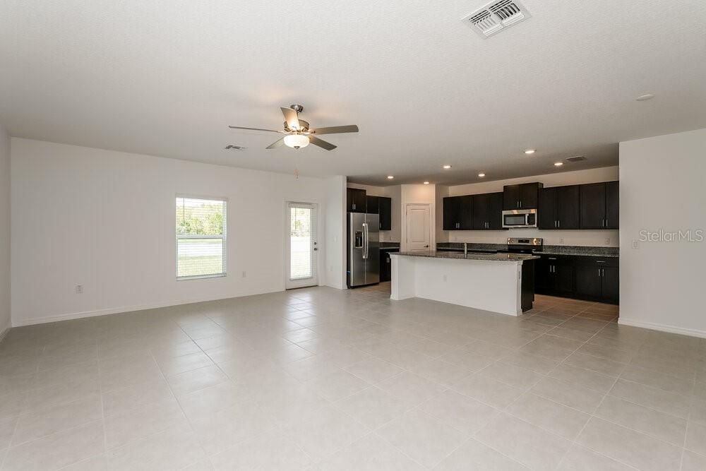 An open-concept living area features light tile flooring, a ceiling fan, and a dark-cabinet kitchen — 1993 SKYBROOKE BOULEVARD, LUTZ, FL