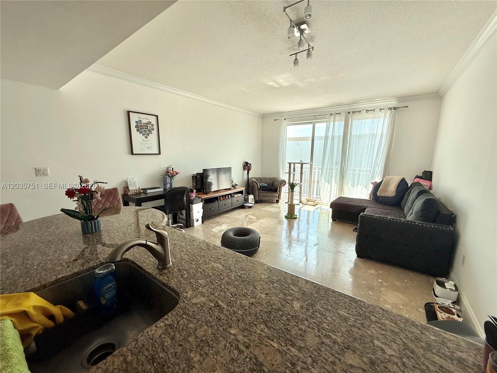 A kitchen island with a granite countertop overlooks an open-concept living room with tile flooring — 7275 SW 90th St # C313, Miami FL 33156, MIAMI, FL
