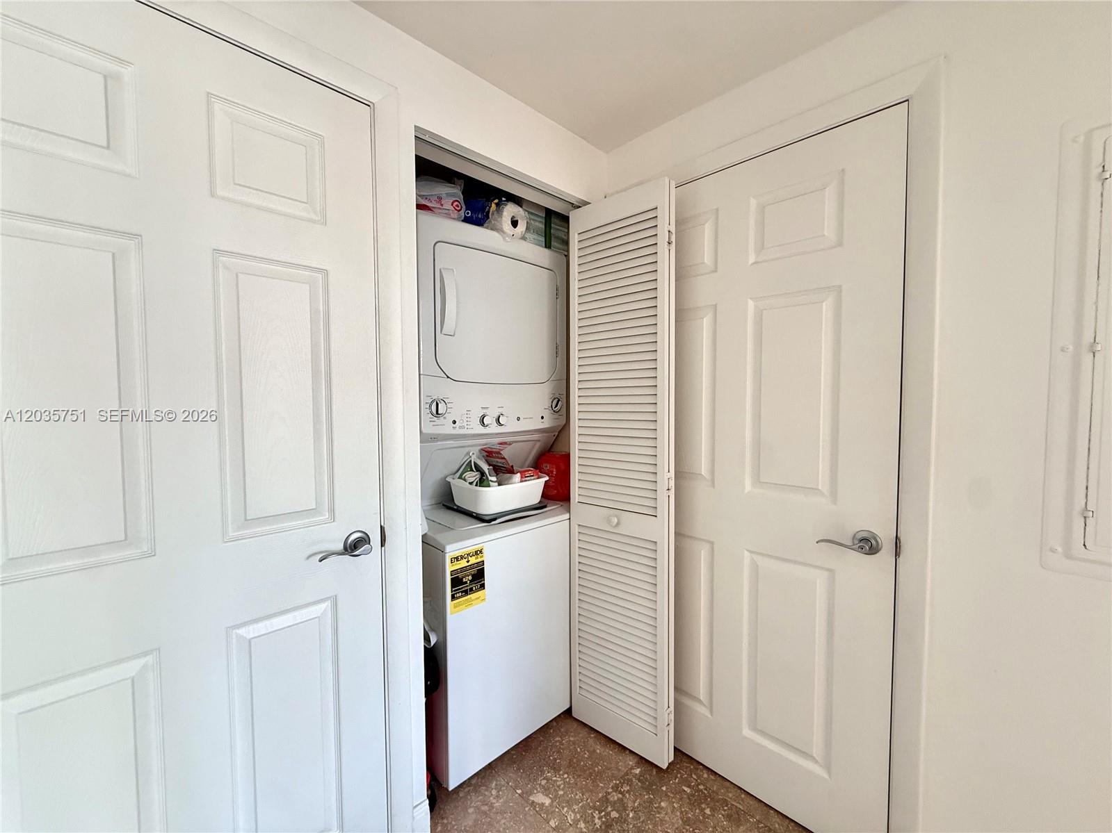 A laundry closet with a stacked washer and dryer sits between two white doors — 7275 SW 90th St # C313, Miami FL 33156, MIAMI, FL