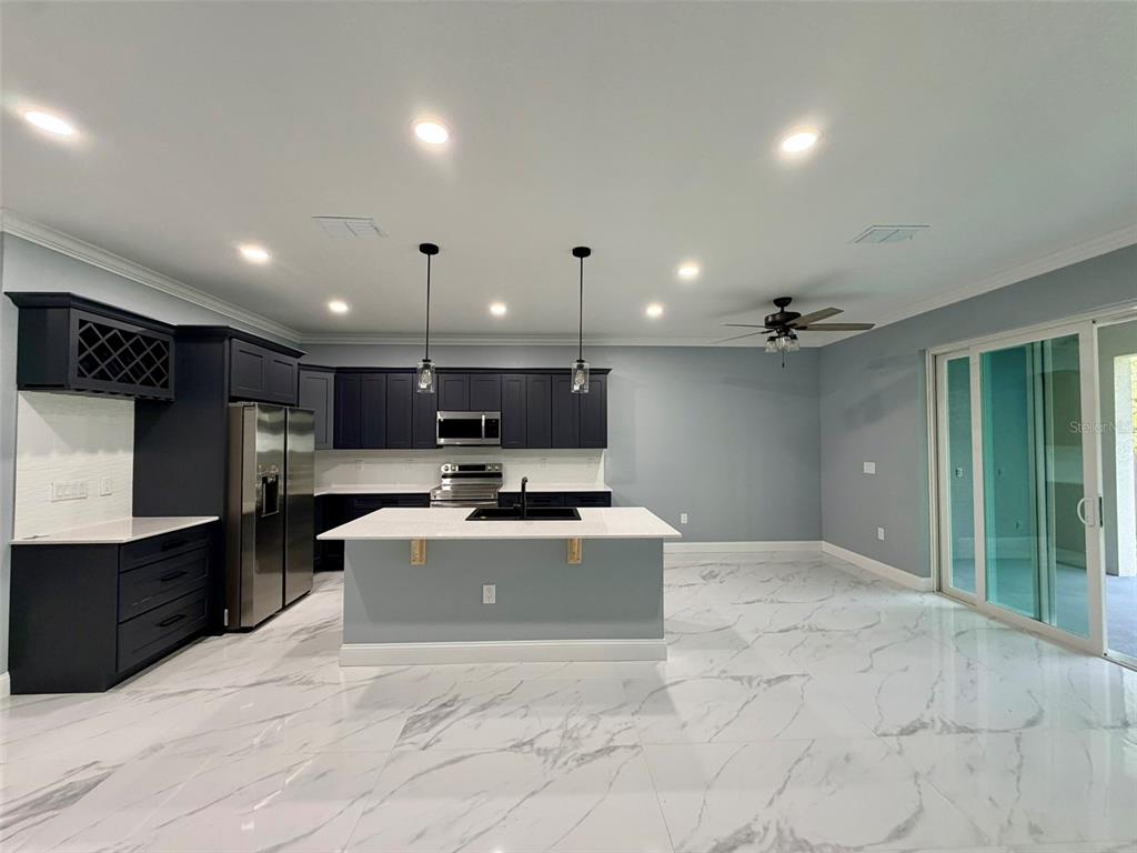 A modern kitchen features dark cabinetry, a white island, and white marble-patterned tile flooring — 1450 IRMA ROAD, EUSTIS, FL