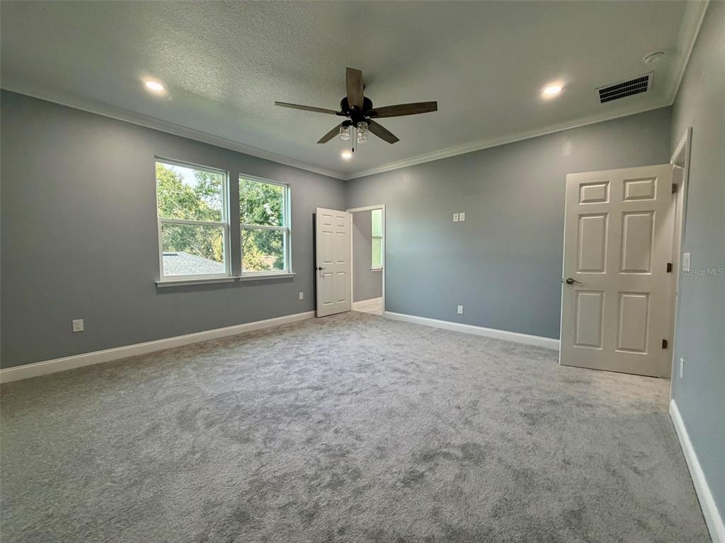 A bedroom with gray walls, gray carpet, a ceiling fan, and two open doorways — 1450 IRMA ROAD, EUSTIS, FL