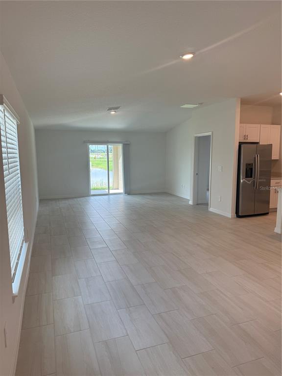 An open-concept living area features light-colored tile flooring, recessed lighting, and a sliding glass door — 32985 TWIN FLOWER AVE, WESLEY CHAPEL, FL