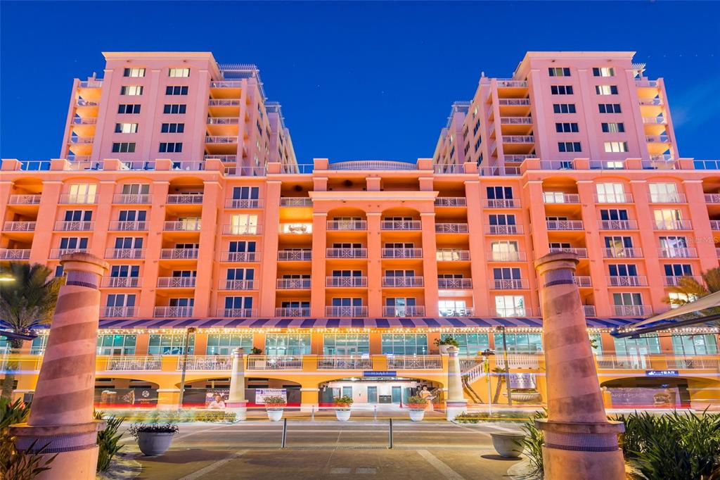A multi-story peach-colored hotel building with balconies and a ground-level entrance at dusk — 301 S GULFVIEW BOULEVARD UNIT 304, CLEARWATER BEACH, FL
