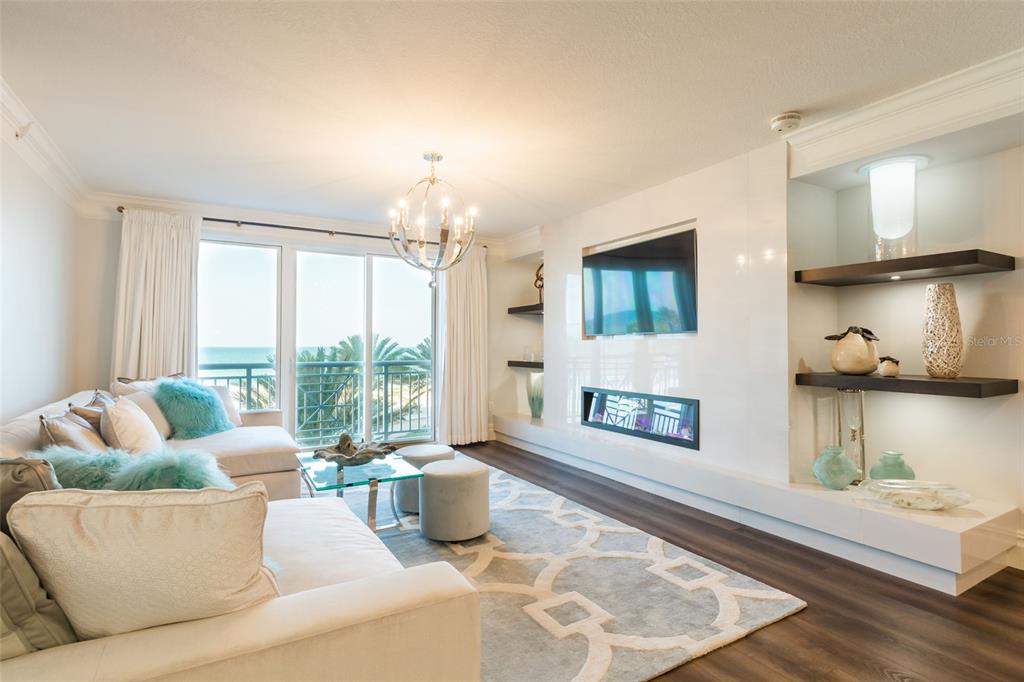 A living room features a white sofa, a fireplace, wall shelving, and a balcony view — 301 S GULFVIEW BOULEVARD UNIT 304, CLEARWATER BEACH, FL