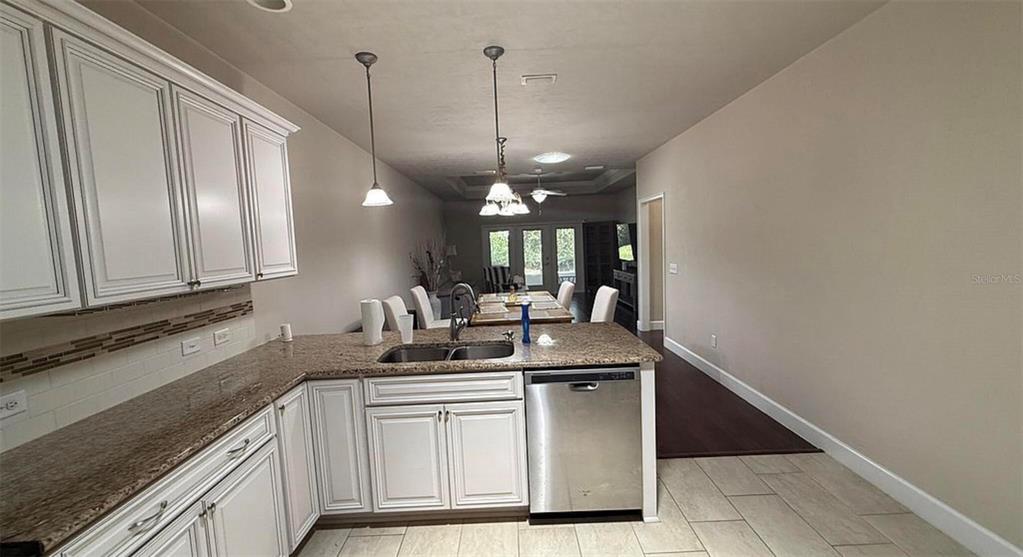 A kitchen with white cabinets and granite countertops overlooks a dining area and living room — 12604 NW 11TH PLACE, NEWBERRY, FL