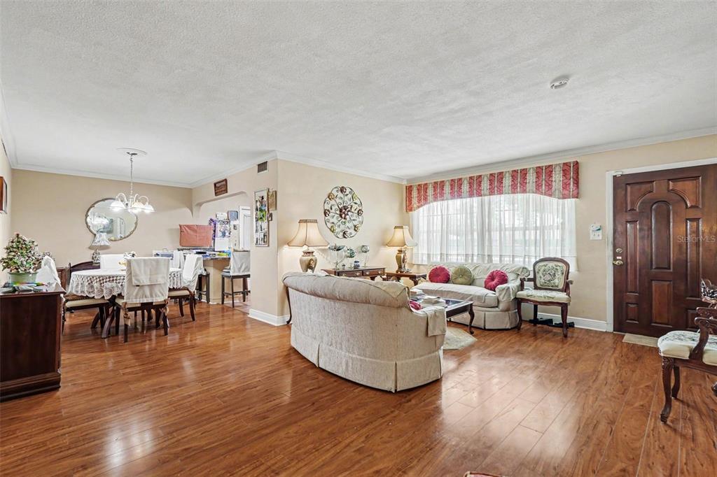A living room and dining area with hardwood floors, neutral walls, and a wooden front door — 8948 108TH STREET N, SEMINOLE, FL