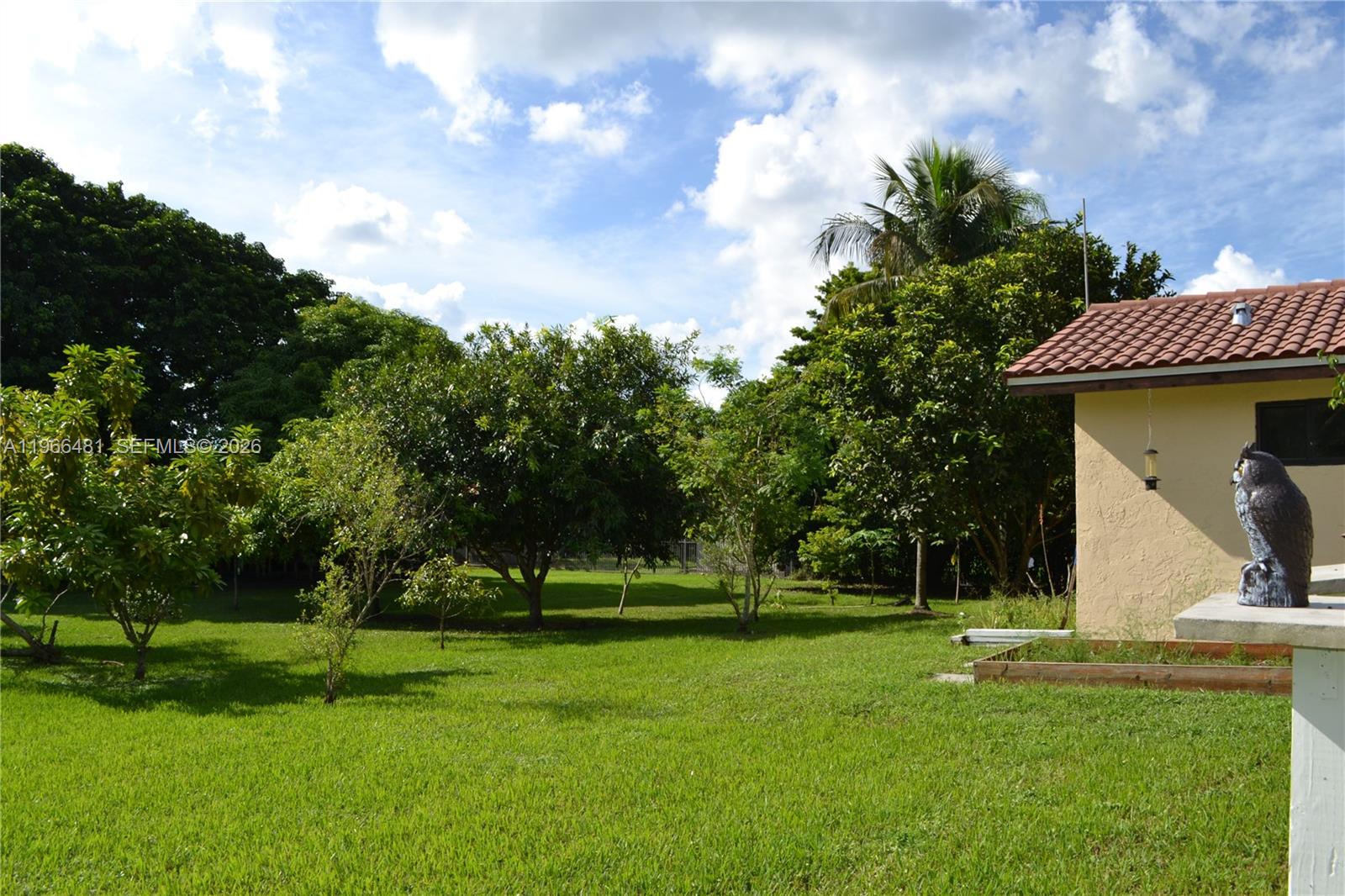 A grassy backyard features several trees and a house with a tiled roof — 5425 SW 190th Ave # 1, Southwest Ranches FL 33332, SOUTHWEST RANCHES, FL