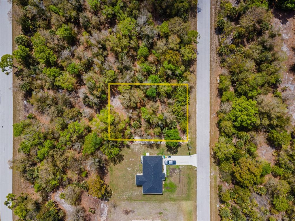 An aerial view shows a rectangular lot outlined in yellow next to a paved road — 7084 LIPPMAN ROAD, PORT CHARLOTTE, FL